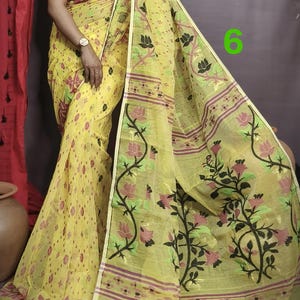 May include: A yellow saree with a floral pattern and a red border. The saree is made of a lightweight fabric and has a delicate, feminine feel.