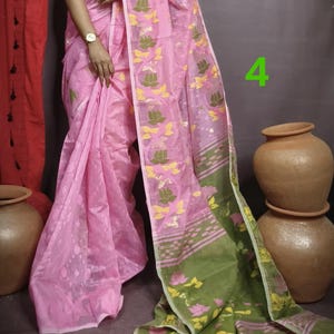 May include: A pink and green saree with a floral pattern. The saree has a pink base with green and yellow floral designs. The saree is draped around a person's body.