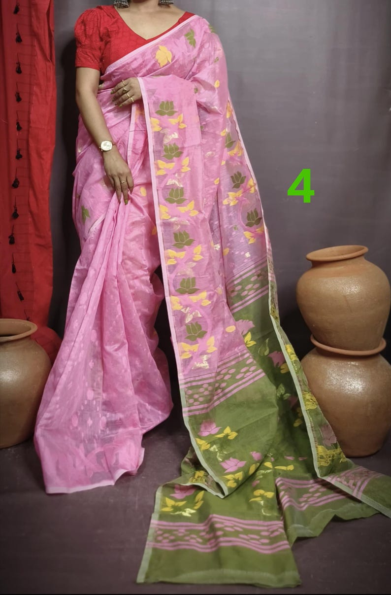 May include: A pink and green saree with a floral pattern. The saree has a pink base with green and yellow floral designs. The saree is draped around a person's body.