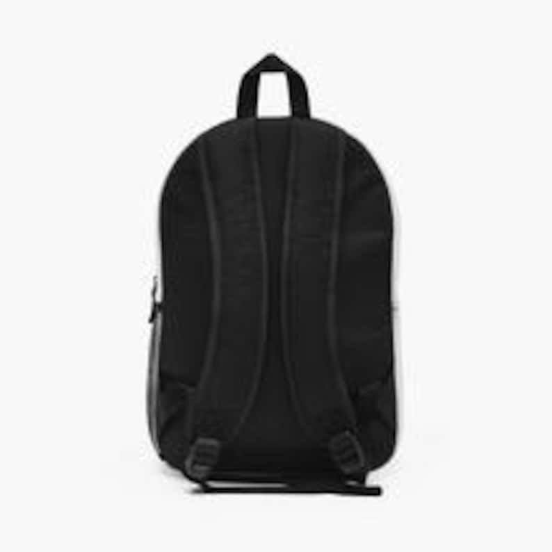 Puede incluir: Mochila negra con una franja blanca en el lateral. Cuenta con correas ajustables para los hombros, un asa superior y un bolsillo frontal con cremallera. La parte trasera es negra con dos secciones verticales acolchadas.