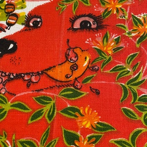 Puede incluir: Primer plano de una tela roja con un patrón floral. La tela presenta hojas verdes, flores naranjas y una cara de animal de dibujos animados con ojos grandes.