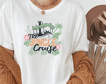 May include: White t-shirt with a graphic of a boat, jungle foliage, and the text "The Jungle Cruise" in orange and black.