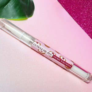 May include: A clear cuticle oil pen with a white applicator tip. The pen has a label that says "Cuticle Oil Pen Cherry Bakewell".