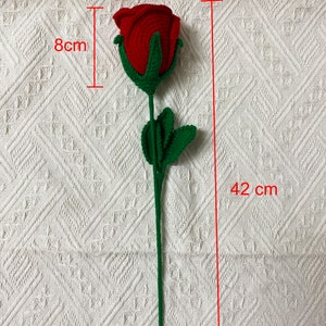 May include: A crocheted red rose with green leaves and stem. The rose is 6 inches wide and 8 inches tall. The stem is 42 inches long.