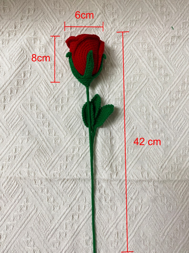 May include: A crocheted red rose with green leaves and stem. The rose is 6 inches wide and 8 inches tall. The stem is 42 inches long.