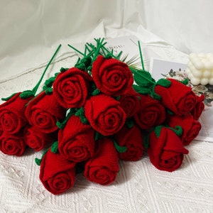 May include: A bouquet of crocheted red roses with green leaves and stems.