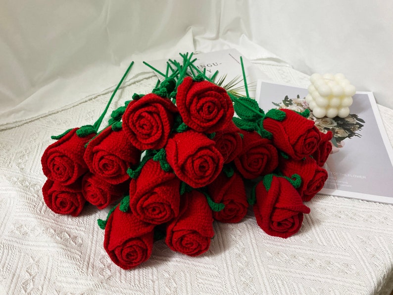 May include: A bouquet of crocheted red roses with green leaves and stems.