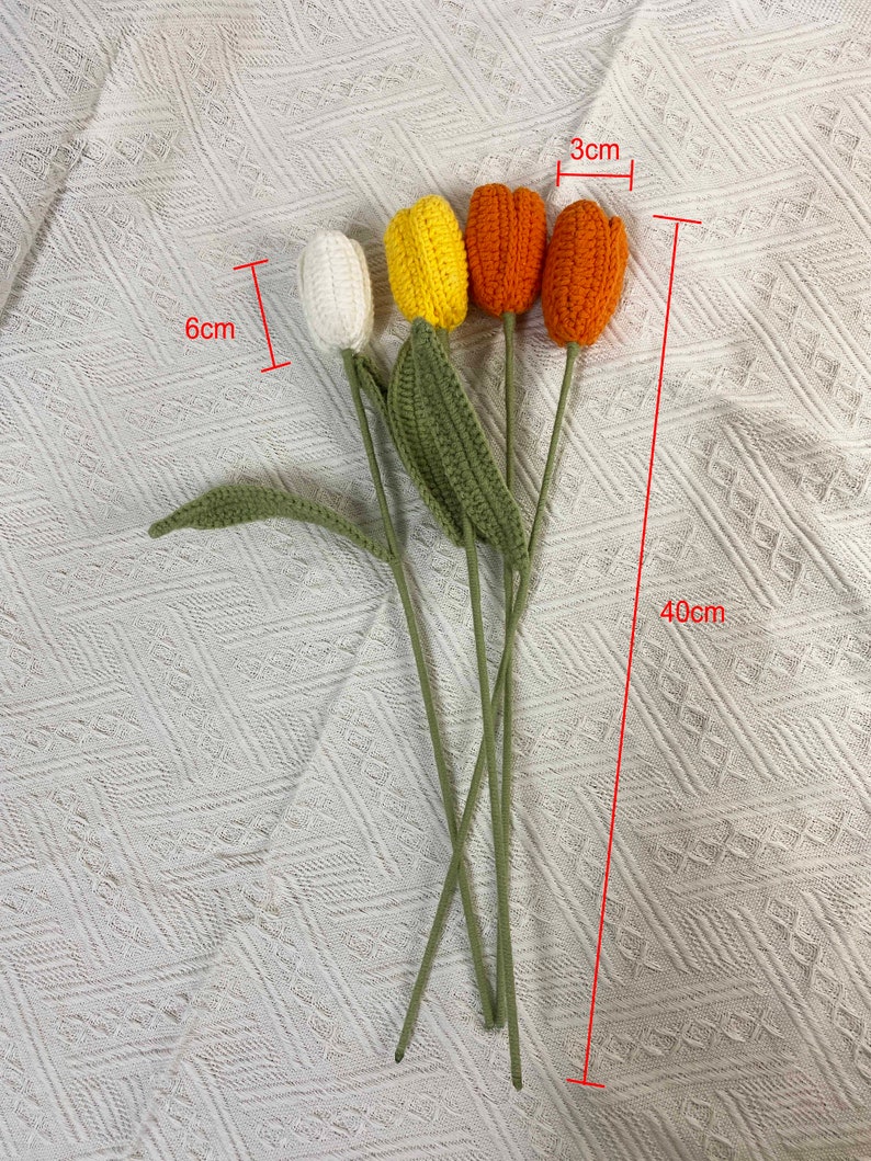 May include: A bouquet of four crocheted tulips in white, yellow, and orange. The tulips are 3 inches tall and the stems are 40 inches long.