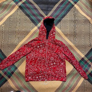 May include: Red hooded jacket with a white bandana print. The jacket has a zipper closure and a drawstring hood.