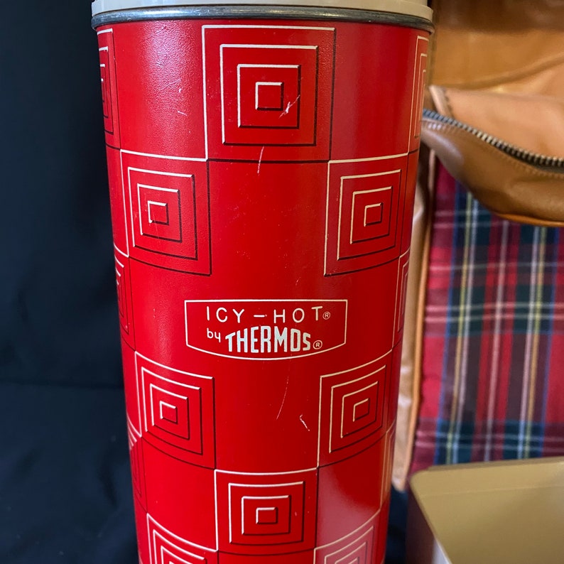 Op de afbeelding: Rode thermos met een wit en zwart geometrisch patroon. De thermos heeft de tekst "ICY-HOT by THERMOS" op de voorkant.