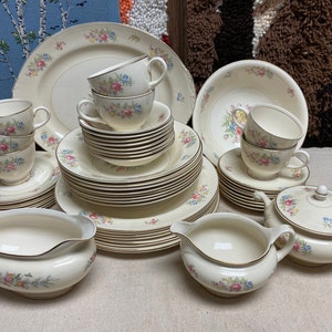 May include: A vintage set of white china dinnerware with a floral pattern in shades of pink, blue, and yellow. The set includes plates, bowls, cups, saucers, a creamer, and a sugar bowl.