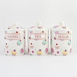 May include: Set of three white ceramic canisters with cupcake designs. The canisters have lids and are labelled "Coffee", "Tea", and "Sugar".