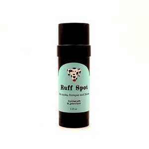 May include: A black cylindrical product labeled "Ruff Spot" with a light blue label. The label features a dalmatian dog illustration and text indicating the product is for hot spots, scrapes, and itches. It is enriched with St. John's Wort and contains 2.25 oz.