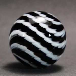May include: A black and white glass marble with a swirling pattern. The marble features alternating bands of black and white, creating a striped effect. The surface is glossy and reflects light, highlighting the intricate design. This decorative marble is a unique collectible.