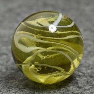 May include: A yellow glass marble with white swirls. The marble has a glossy finish.