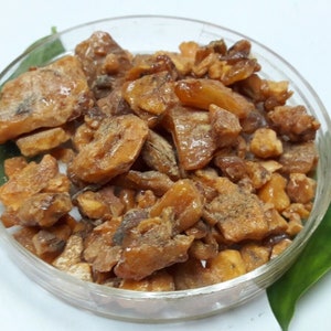 Puede incluir: Primer plano de un plato de vidrio transparente lleno de piezas de resina marrón de forma irregular.