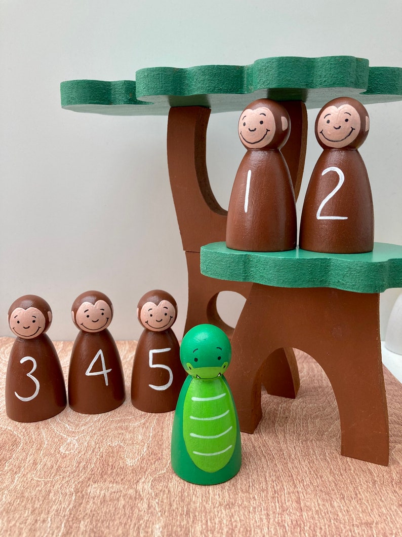 May include: Wooden toy set featuring a tree with a green canopy and brown trunk. Five brown monkey figures with white numbers 1-5 and a green alligator figure are included. The figures are designed for educational play.