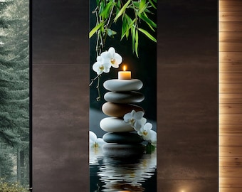 May include: A zen-inspired wall art print featuring a stack of smooth, gray and brown stones with a lit candle on top. White orchids and green bamboo leaves are in the background, reflected in the water below.