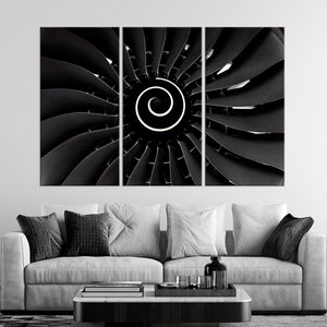 May include: A black and white photograph of a jet engine with a spiral design in the center. The engine is split into three sections, with the center section showing the spiral design.