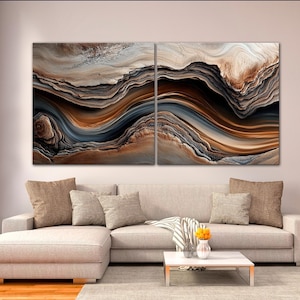 a modern living room with a large abstract painting hanging on the wall above a beige sofa with throw pillows. The sofa is positioned in front of a coffee table with a vase of flowers on it. The room has a wooden floor and a window with blinds, creating a cozy and inviting atmosphere.