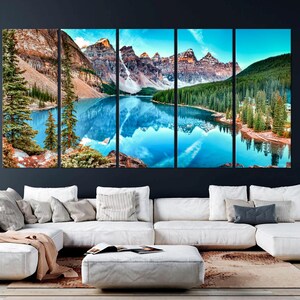 May include: A panoramic view of a mountain lake with snow-capped peaks reflected in the water. The lake is surrounded by lush green trees and the mountains are a mix of brown and green.