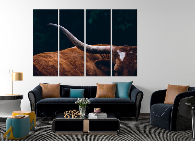 May include: A close-up of a brown and white longhorn steer with large horns. The steer is looking to the right of the frame. The background is dark and blurry.