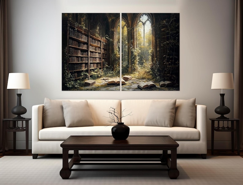 May include: A two-panel wall art set depicting a dark, overgrown library interior with tall bookshelves, open books scattered on a stone floor, and large arched windows letting in golden light, displayed above a cream-coloured sofa.