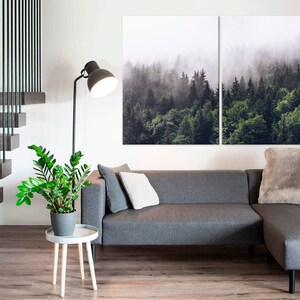 May include: A grey sectional sofa with a fluffy grey throw pillow in a living room with a wooden staircase, a potted plant, and a floor lamp. A large canvas print of a misty forest hangs on the wall above the sofa.
