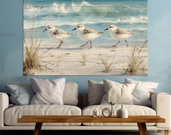 Puede incluir: Impresión artística de pared con temática costera que presenta tres correlimos caminando por una playa arenosa. El fondo representa un océano azul con olas blancas, impreso en un diseño de tablones de madera.