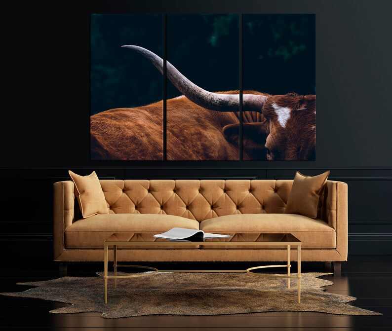 May include: A tri-panel canvas print featuring a close-up of a brown and white longhorn steer with large horns. The steer is set against a dark green background.