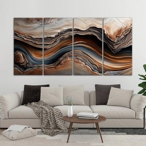 a modern living room with a large abstract painting hanging on the wall above a beige sofa. The painting has a swirling pattern of brown, orange, and gray colors, creating a dynamic and visually striking design. The room also includes a coffee table, a potted plant, and some decorative elements, contributing to the overall stylish and contemporary atmosphere.