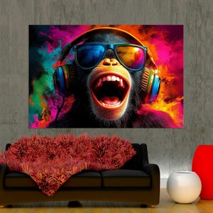 May include: A colourful canvas print of a monkey wearing sunglasses and headphones, with its mouth open in a shout. The background is a vibrant mix of pink, blue, and yellow. The print is displayed above a black sofa with a red throw.