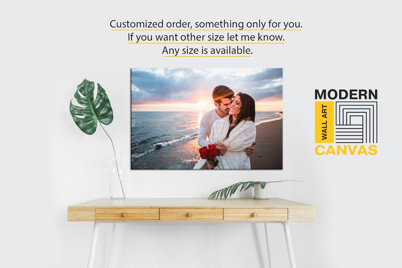 May include: A canvas print depicting a couple embracing on a beach at sunset. The print has a modern design and is available in various sizes. The text "MODERN WALL ART CANVAS" is displayed in the top right corner.