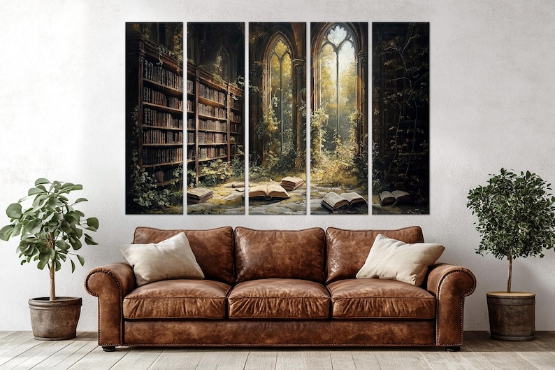 May include: A five-panel wall art set depicting a dark, overgrown library interior with tall arched windows, stone floors, and open books scattered on the ground, positioned above a brown leather sofa with two cream-coloured throw pillows.