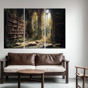 May include: A three-panel wall art set depicting an interior scene of a library with tall wooden bookshelves filled with books, stone floors, open books scattered on the ground, and large arched windows with sunlight streaming into the room.