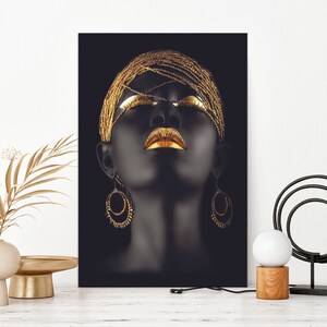 May include: A black and gold portrait of a woman with her eyes closed and lips painted gold. She is wearing a gold beaded headpiece and large gold hoop earrings.