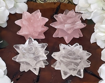 May include: Four crystal starburst shapes, two are clear and two are pink. The crystals are arranged on a wooden slice.