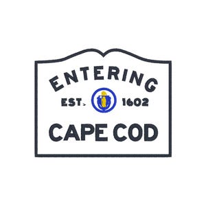 Puede incluir: Un letrero blanco con borde azul oscuro que dice "ENTERING CAPE COD". El letrero también incluye el texto "EST. 1602" y un emblema azul y amarillo. El letrero tiene una parte superior decorativa.