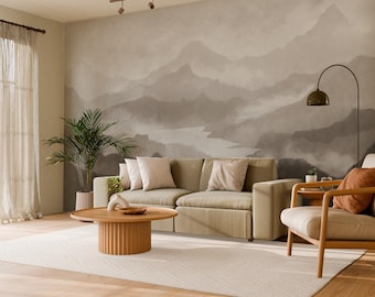 May include: A modern living room with a neutral color palette. A beige sofa with throw pillows sits in front of a mountain mural. A wooden coffee table and armchair complete the space, with a large rug and a potted plant.