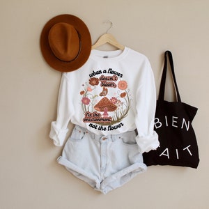 K&ouml;nnte beinhalten: Wei&szlig;er Langarm-Pullover mit einem Pilz-Motiv und dem Text "Wenn eine Blume nicht bl&uuml;ht, repariere die Umwelt, nicht die Blume".