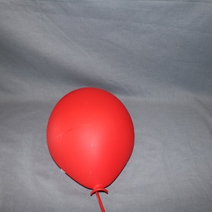 May include: A bright red balloon with a long string attached to the bottom.