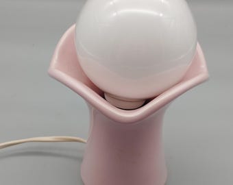 Cute little pink porcelain table lamp with a large light bulb.