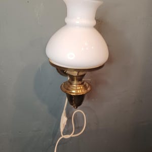 Danish design brass wall lamp in the shape of a petroleum lamp with white glass shade.
