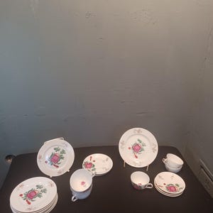 Könnte beinhalten: Ein Set vintage floralem Teegeschirr mit einem rosa-grünen Blumendesign. Das Set enthält sechs Teetassen, sechs Untertassen und sechs Teller.