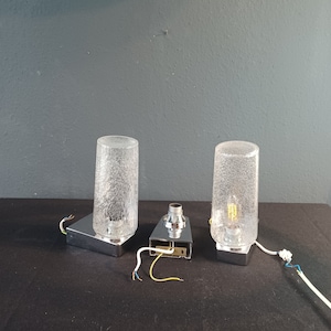 May include: Two chrome wall lights with frosted glass shades. The lights are wired and ready to be installed.