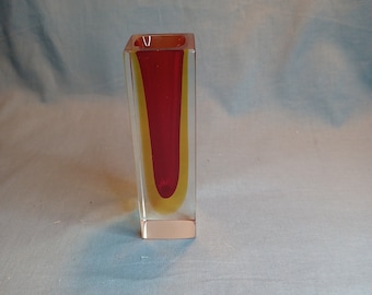 May include: A clear glass vase with a red and yellow interior. The vase is square shaped and has a rectangular opening.