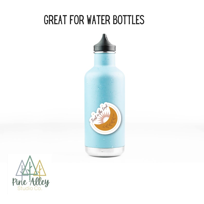 K&ouml;nnte beinhalten: Eine hellblaue Wasserflasche mit einem Aufkleber, auf dem "Trust in the good" steht, mit einem Sonnen- und Monddesign. Der Aufkleber befindet sich auf der Vorderseite der Flasche.