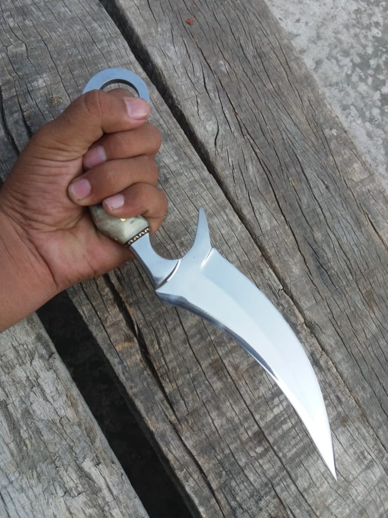 May include: A silver-colored knife with a curved blade and a bone handle. The knife has a ring on the handle for easy grip.