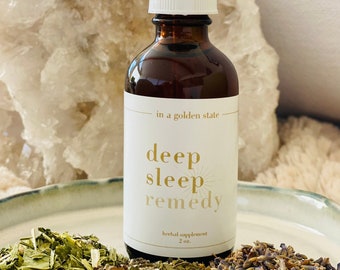 Puede incluir: Una botella de vidrio marrón con un gotero blanco y una etiqueta blanca que dice "in a golden state deep sleep remedy herbal supplement 2 oz."