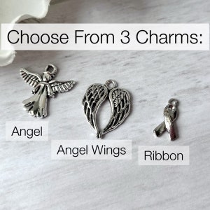 May include: Choose from 3 charms: Angel, Angel Wings, Ribbon. The charms are silver and have a detailed design.